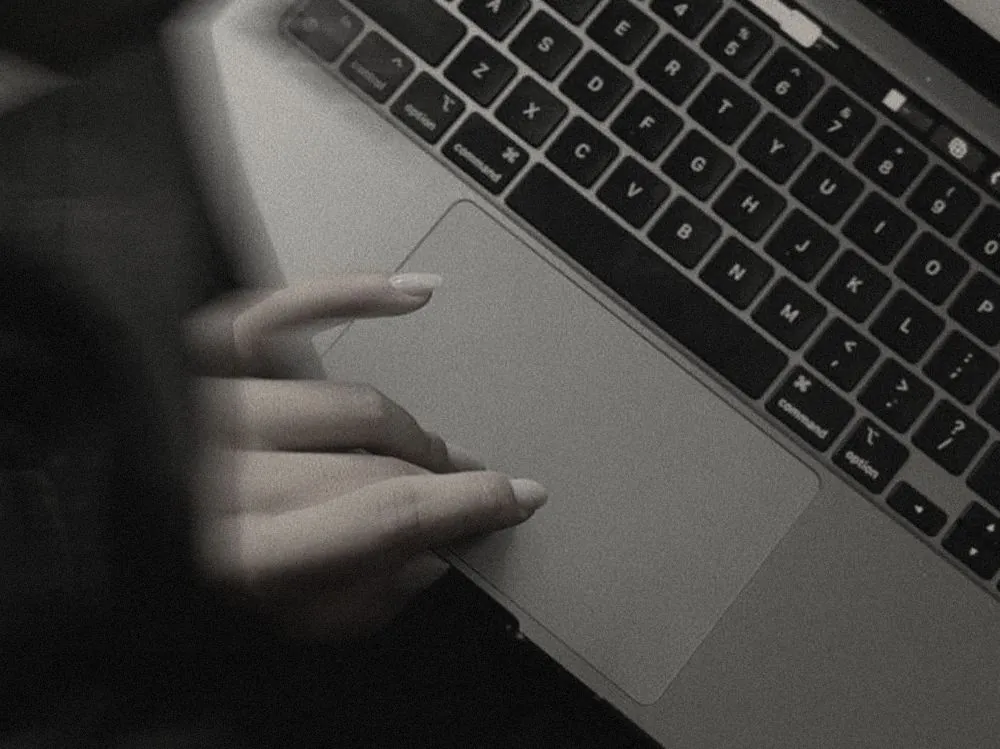 A hand resting on a laptop trackpad