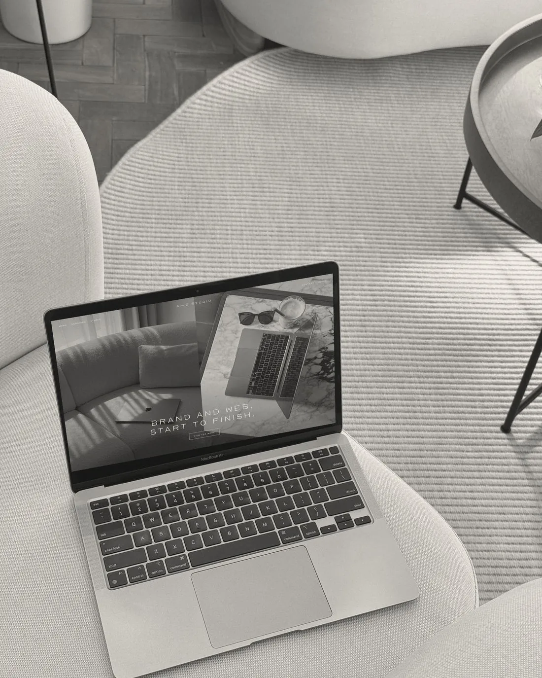 A MacBook Air on a linen armchair showing the A—Z Studio website