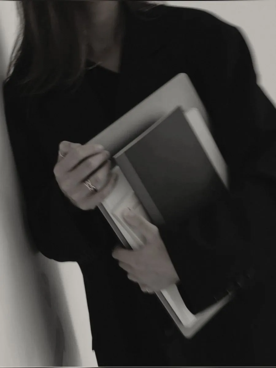 Someone in black holding a laptop close