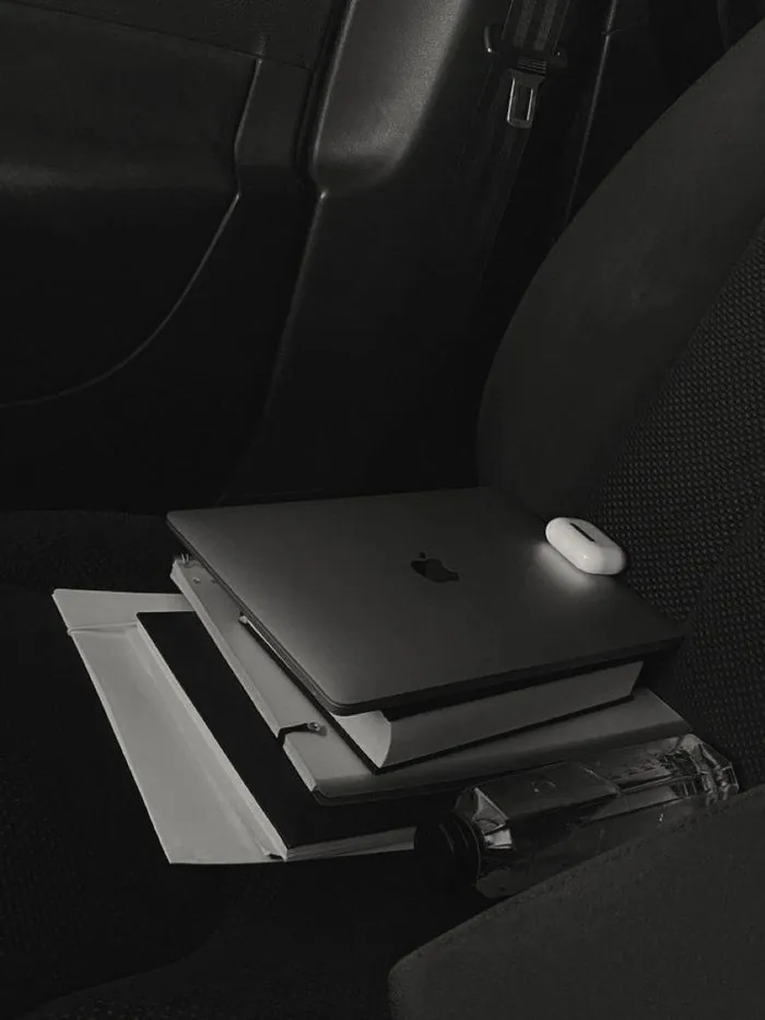 A laptop and notebooks stacked on a dark chair
