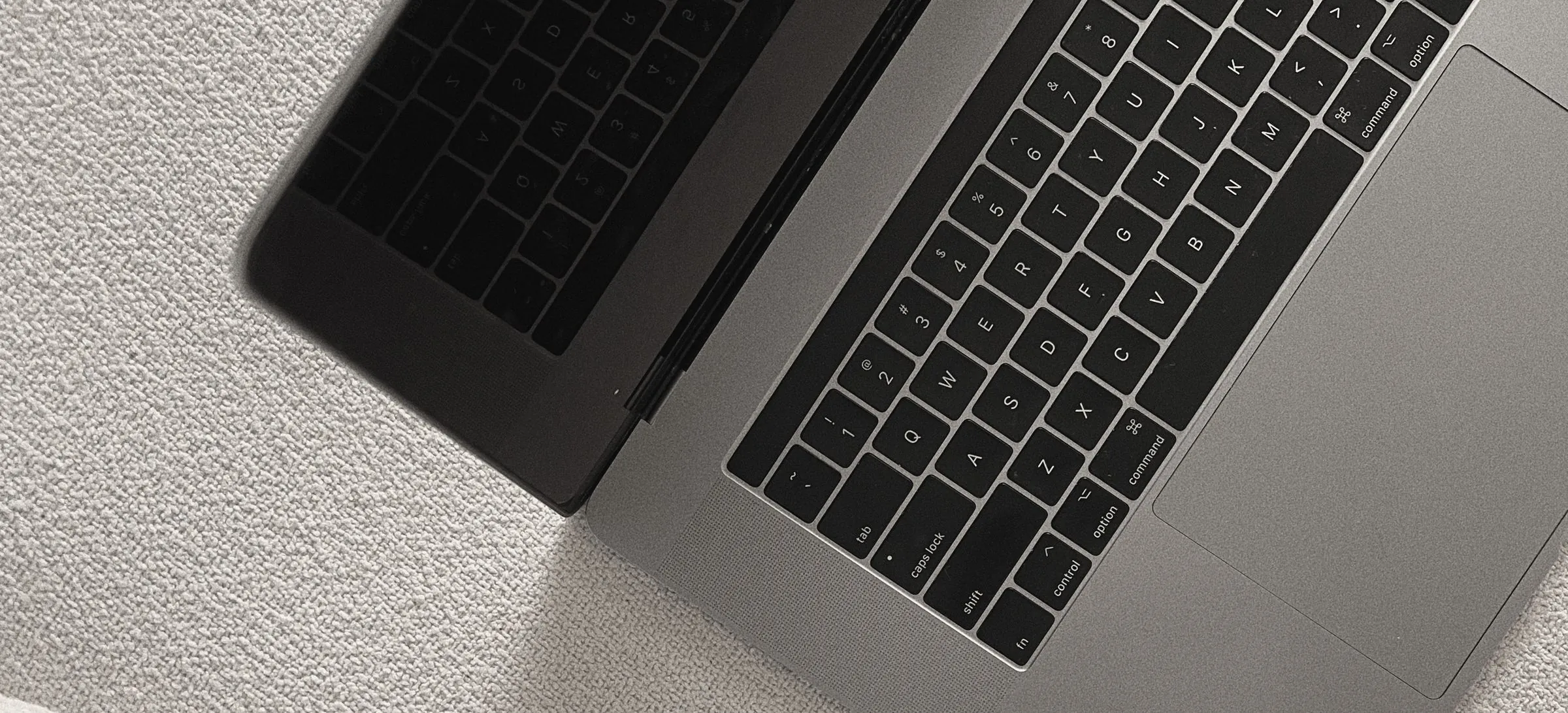 Looking down on an open laptop keyboard on a cream boucle surface