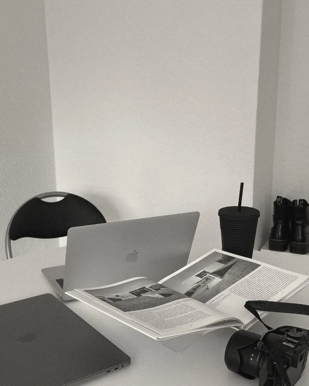 A desk with an open laptop, a magazine layout and a camera