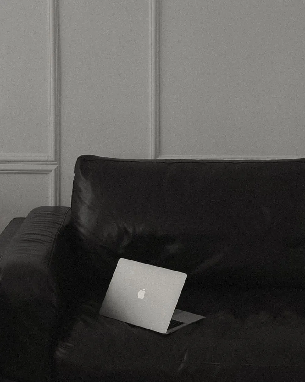 An open silver laptop on a dark leather sofa